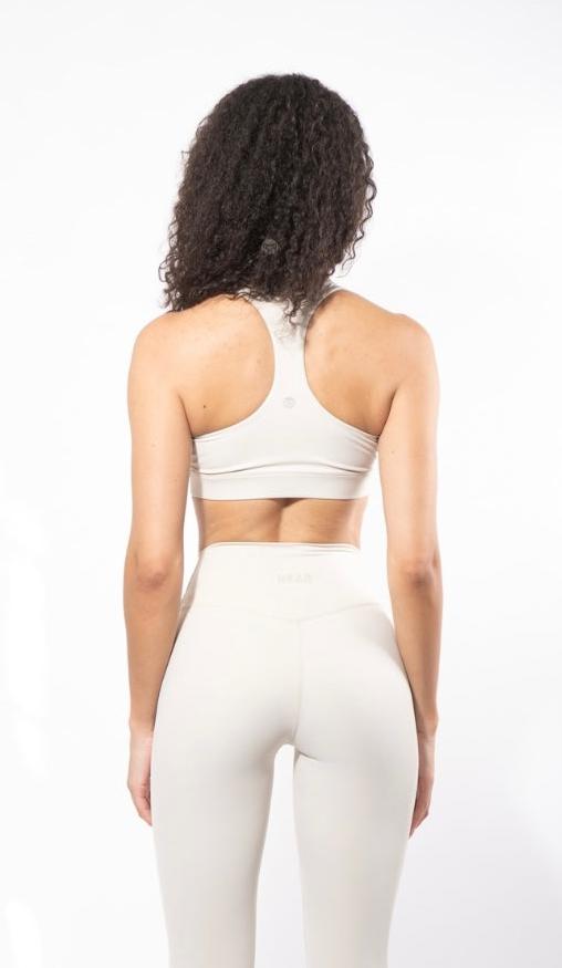 girl from behind wearing a sculpting yoga bra in beige